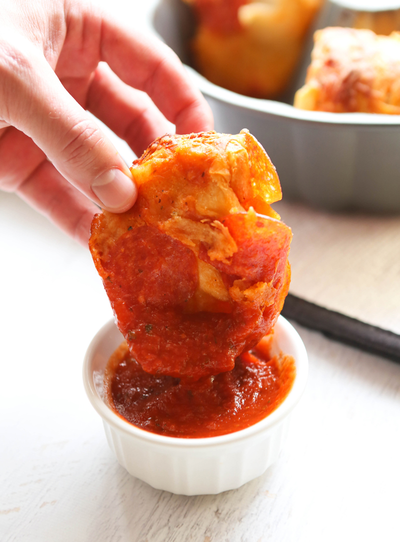 hand dunking bread in marinara sauce