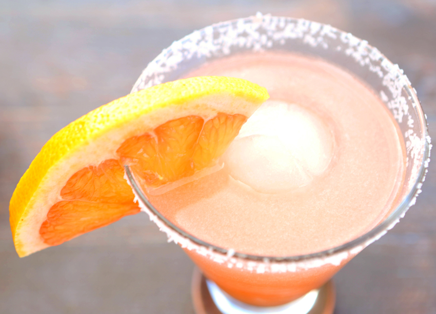 Top view of a salty dog drink with sa salted rim on the glass and a grapefruit slice on the rim