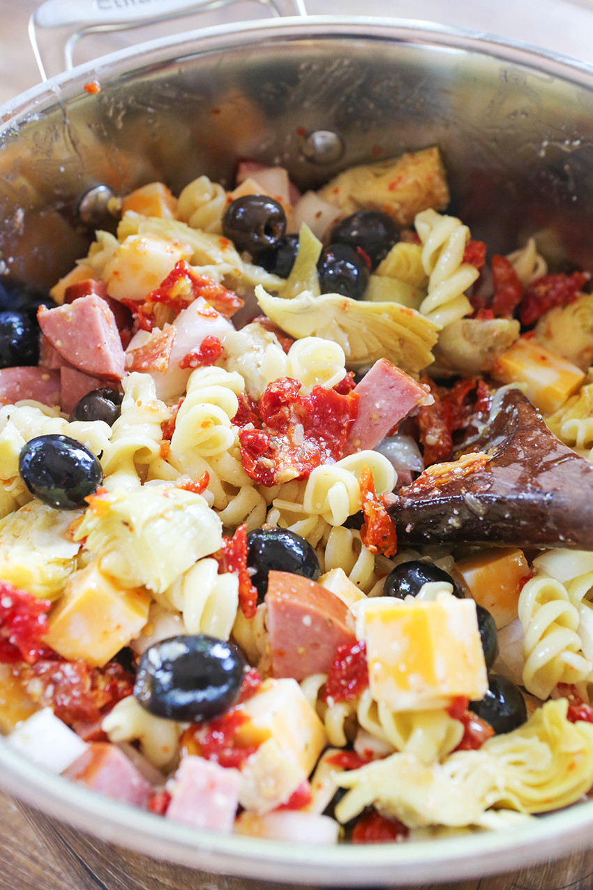 larget saucepan filled with pasta salad with a wooden spoon sticking out of it