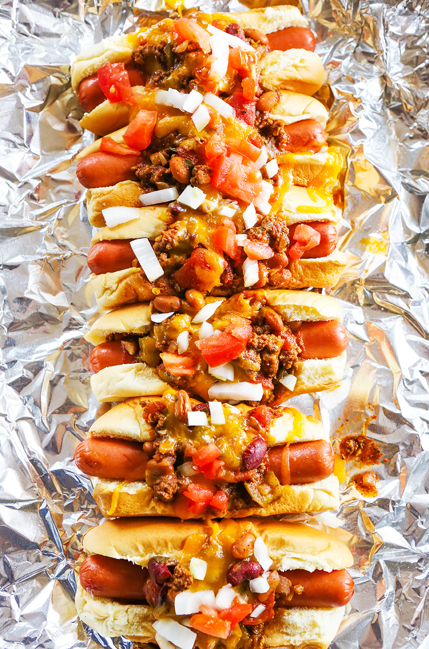 Looking straight down onto a baking sheet lined with loaded chili dogs.