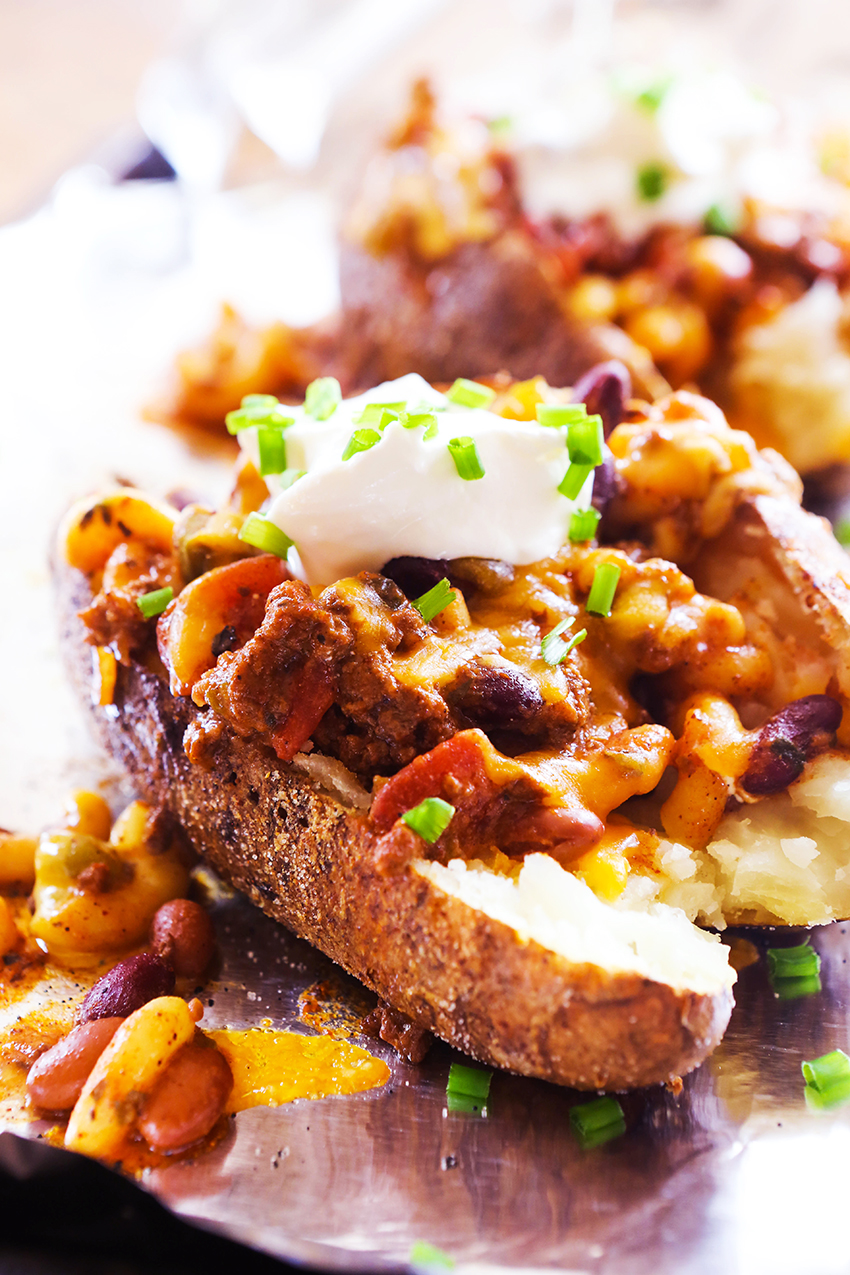 Chili-topped baked potato with sour cream and chives on top.