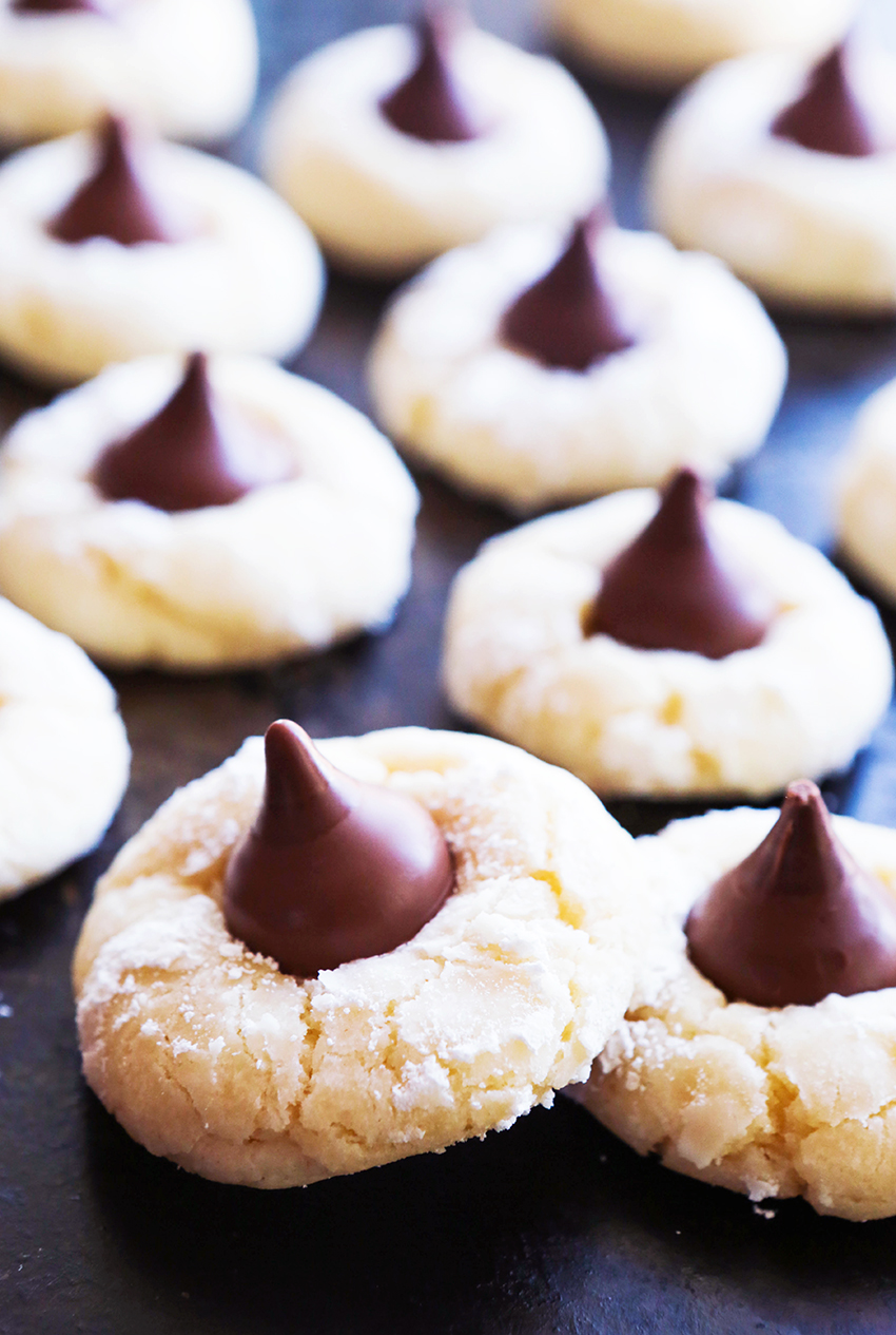 cream cheese cookies with kisses pressed into them lined up on a baking sheet