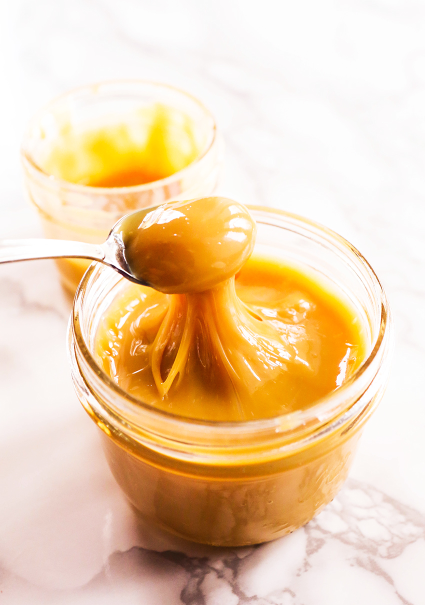 spoon pulling dulce de leche out of a mason jar