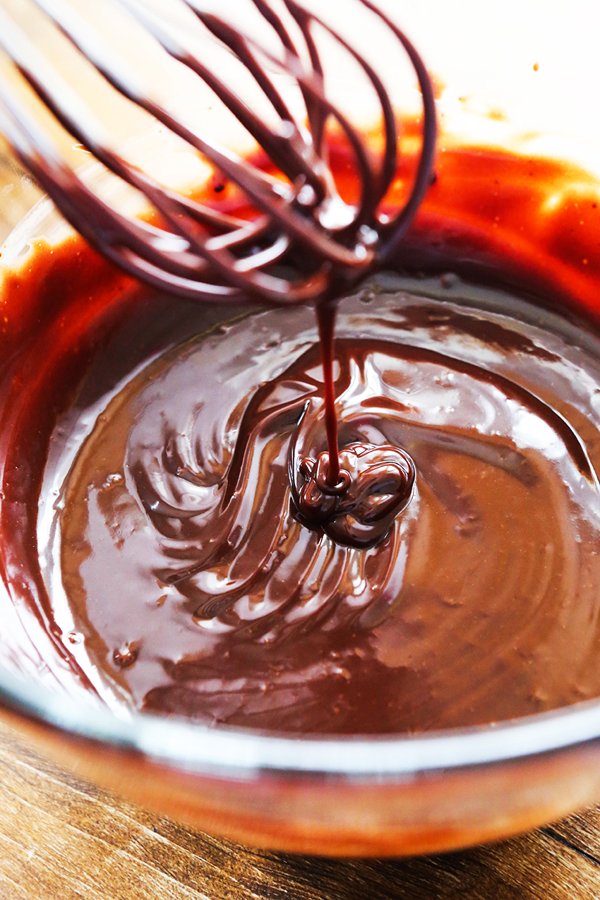 whisk dripping chocolate ganache into a bowl full of creamy chocolate