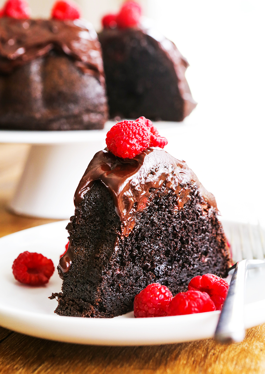 perfect piece of chocolate cake on a white plate topped with fresh raspberries