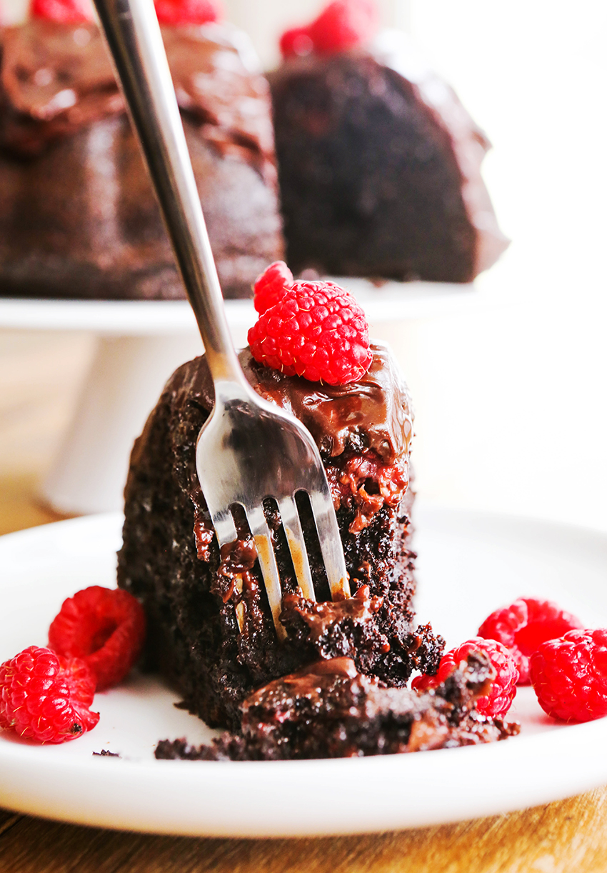 Fork stuck into a piece of chocolate cake with raspberries around it