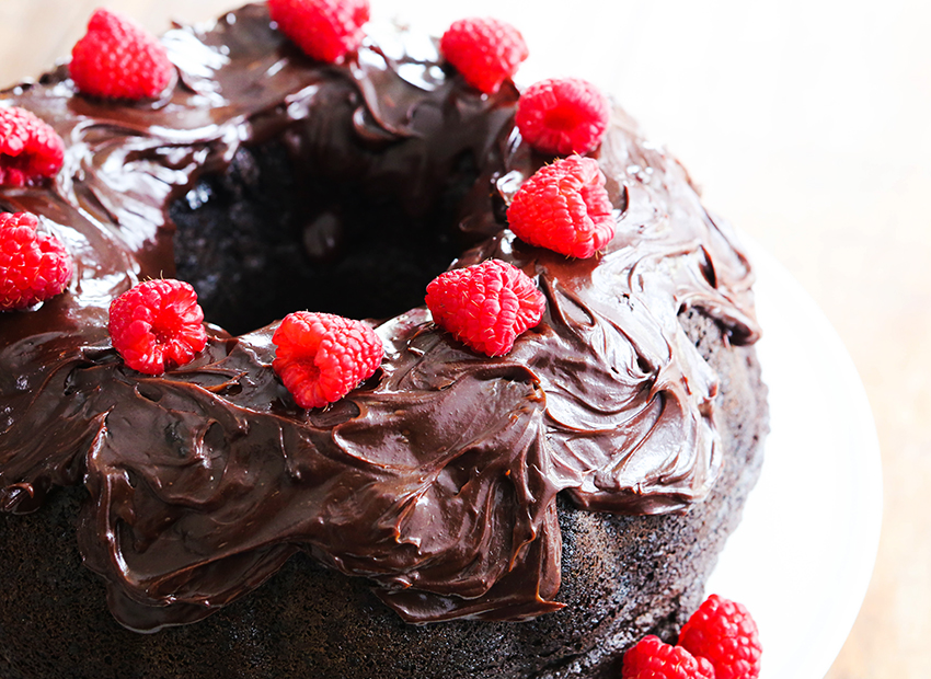 top view of a chocolate bundt cake with chocolate frosting and raspberries