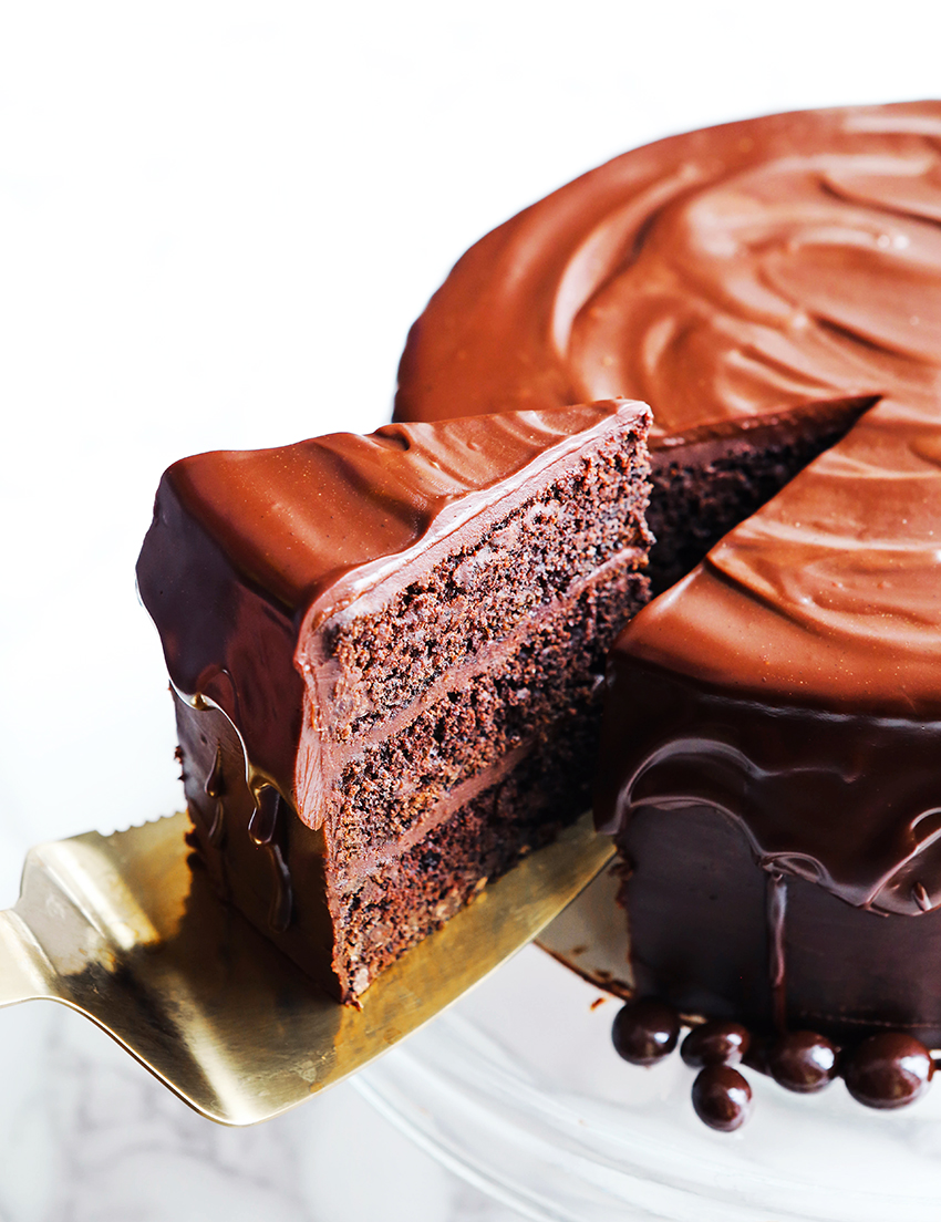 slice of chocolate cake being pulled out of a three layer cake