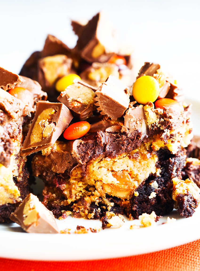 reese's peanut butter cheesecake brownies close up and piled high with sugary ingredients