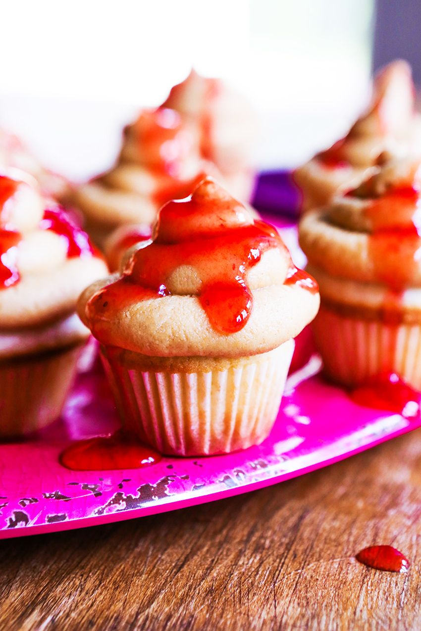 peanut butter cupcakes lined up on a plate with jelly drizzled over the top