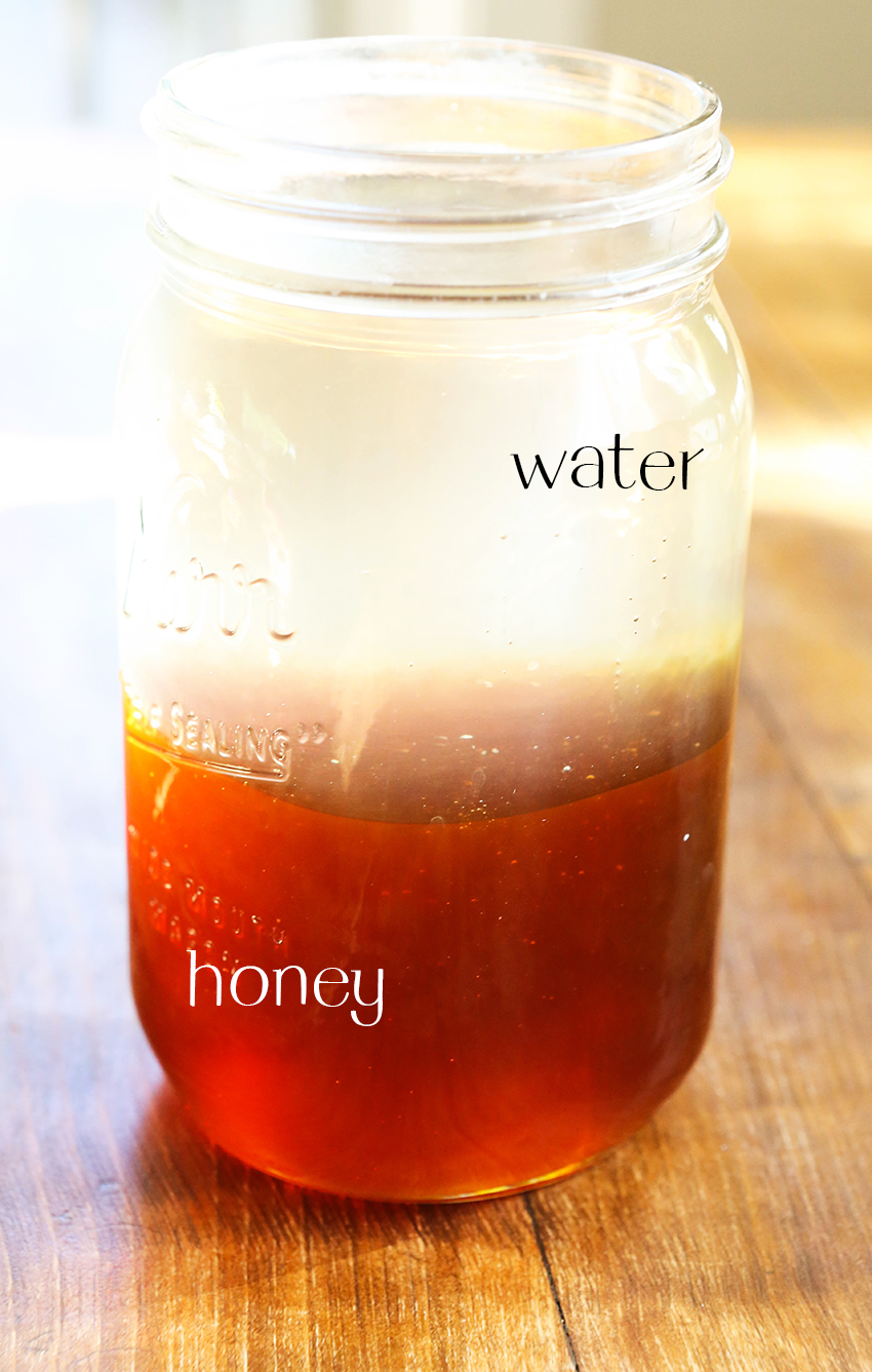 Close up of a glass jar filled with water and honey sitting on a table