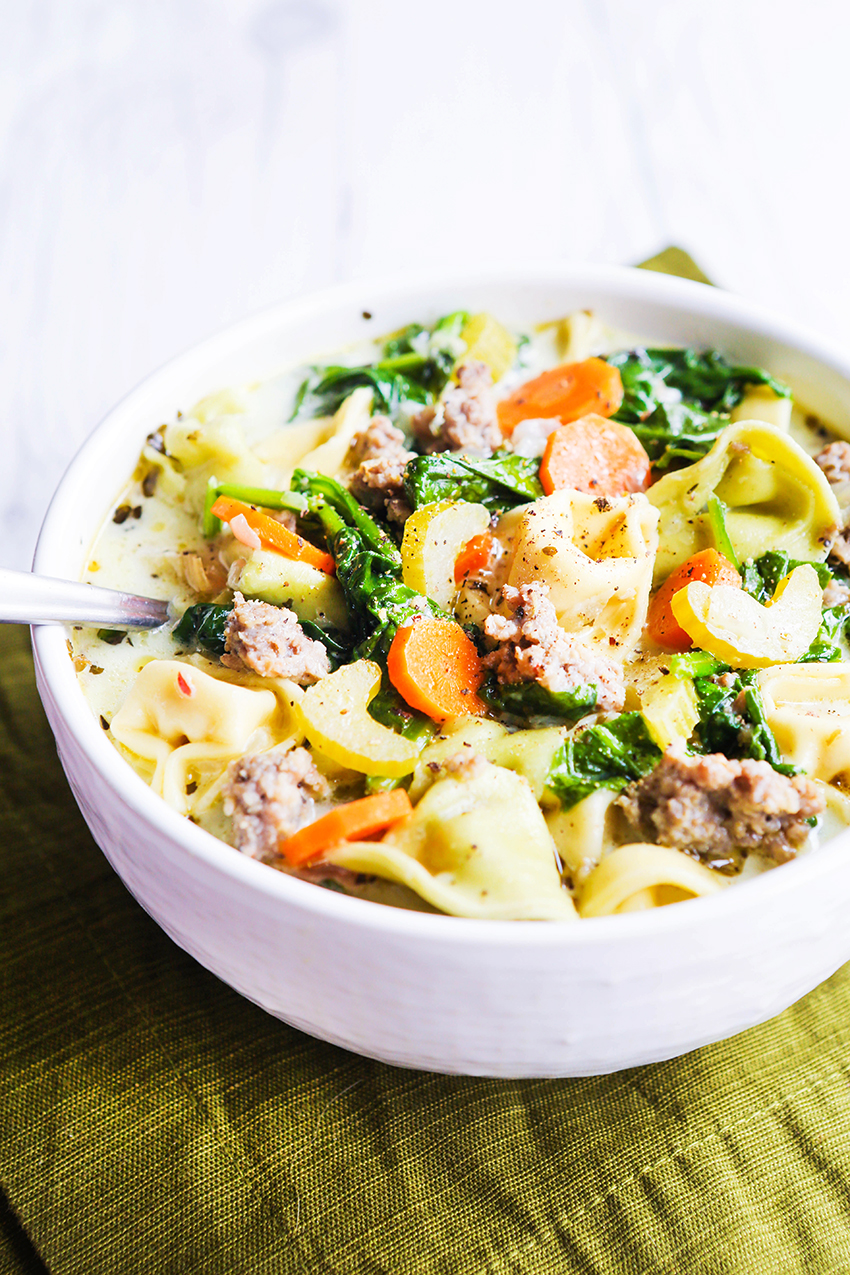 perfect looking bowl of soup filled with sausage, pasta, carrots and spinach