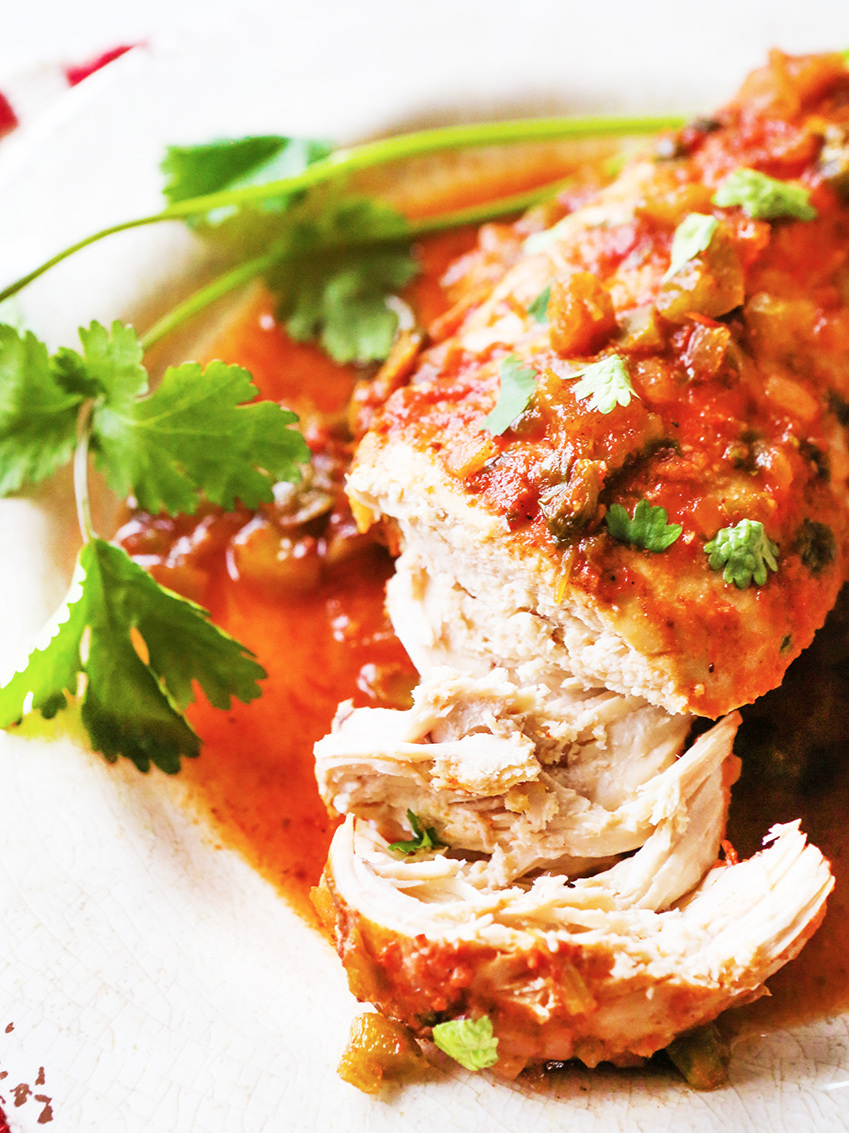 cooked chicken breast on a plate covered in salsa and cilantro
