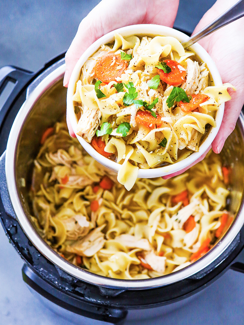  Top view hands holding view of chicken noodle soup over Instant Pot 
