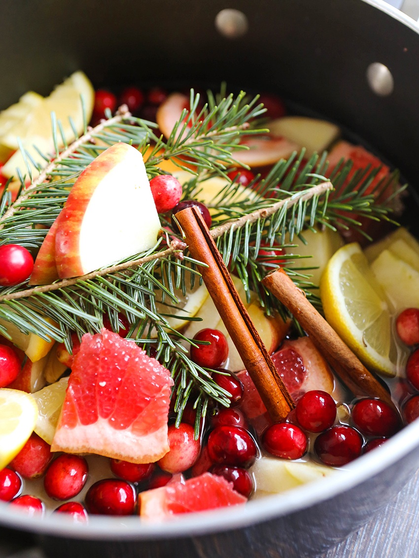 cinnamon sticks and pine branches in a bowl with apples and citrus