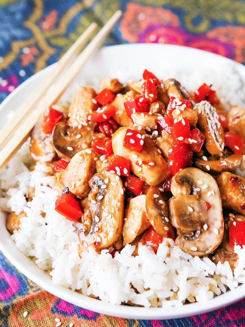 Plate of white rice and hoisin chicken   on top with chopsticks on the side of the plate