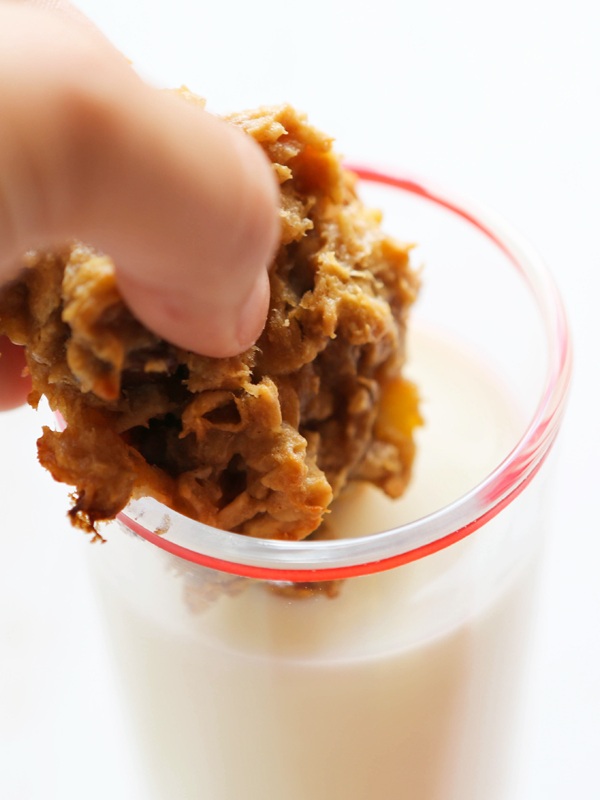 fingers dunking a cookie into a glass of milk