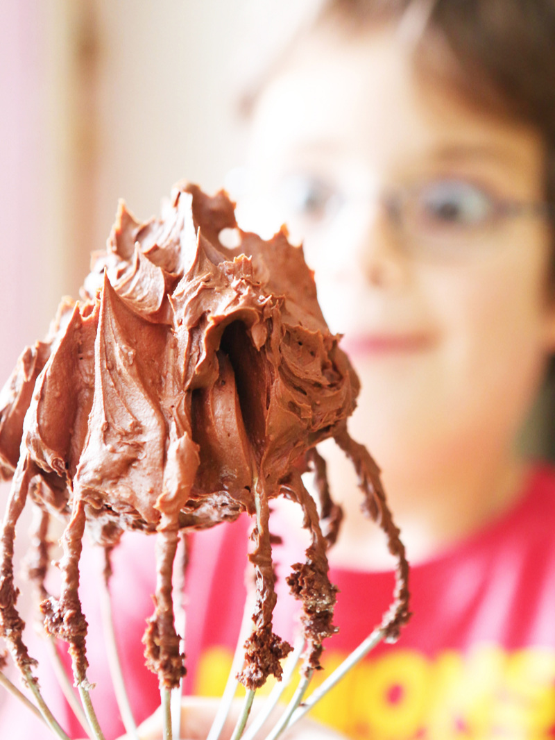 chocolate buttercream on whisk attachment being held by a cute boy with wide eyes