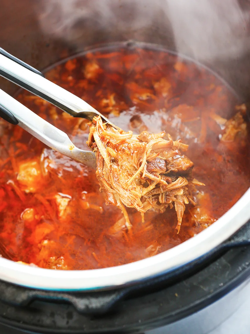  Tongs pulling bbq pulled pork out of Instant Pot 
