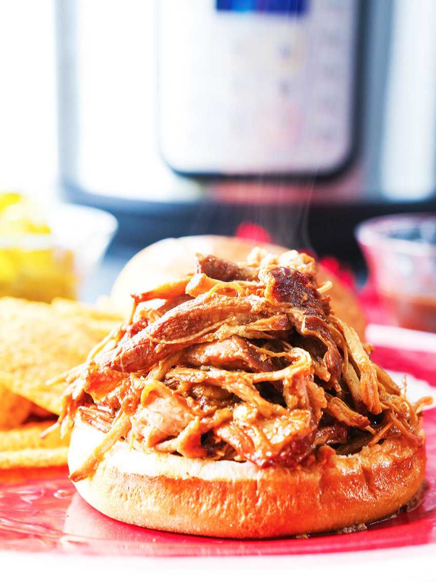 Pile of pulled pork on bottom bun with Instant Pot in background 