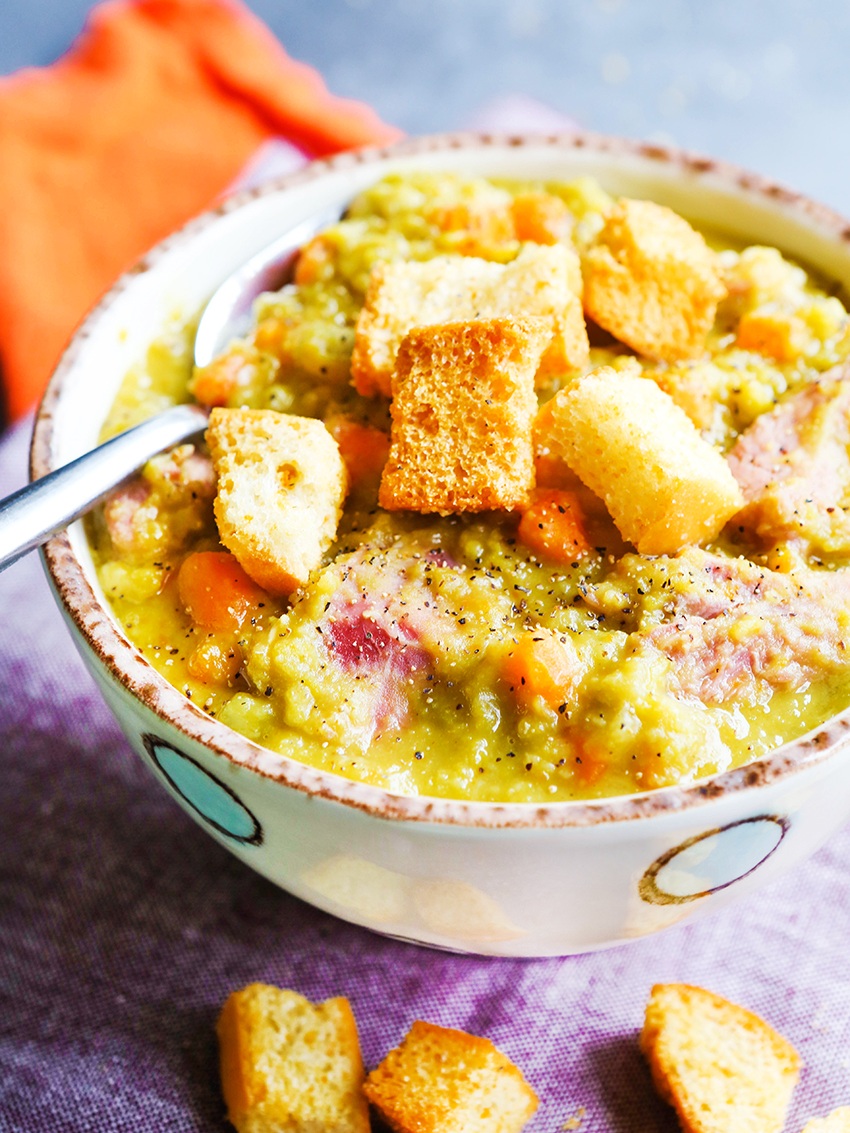 colorful heaping bowl of pea and ham soup with giant croutons on top