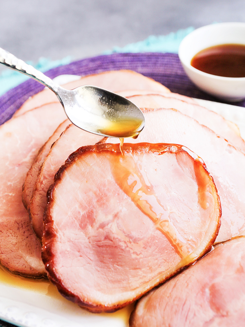 Spoon drizzling glaze over instant pot ham slices 