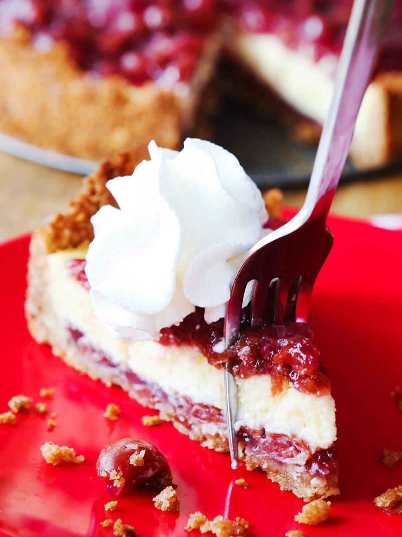 fork sticking into a piece of baked cherry cheesecake