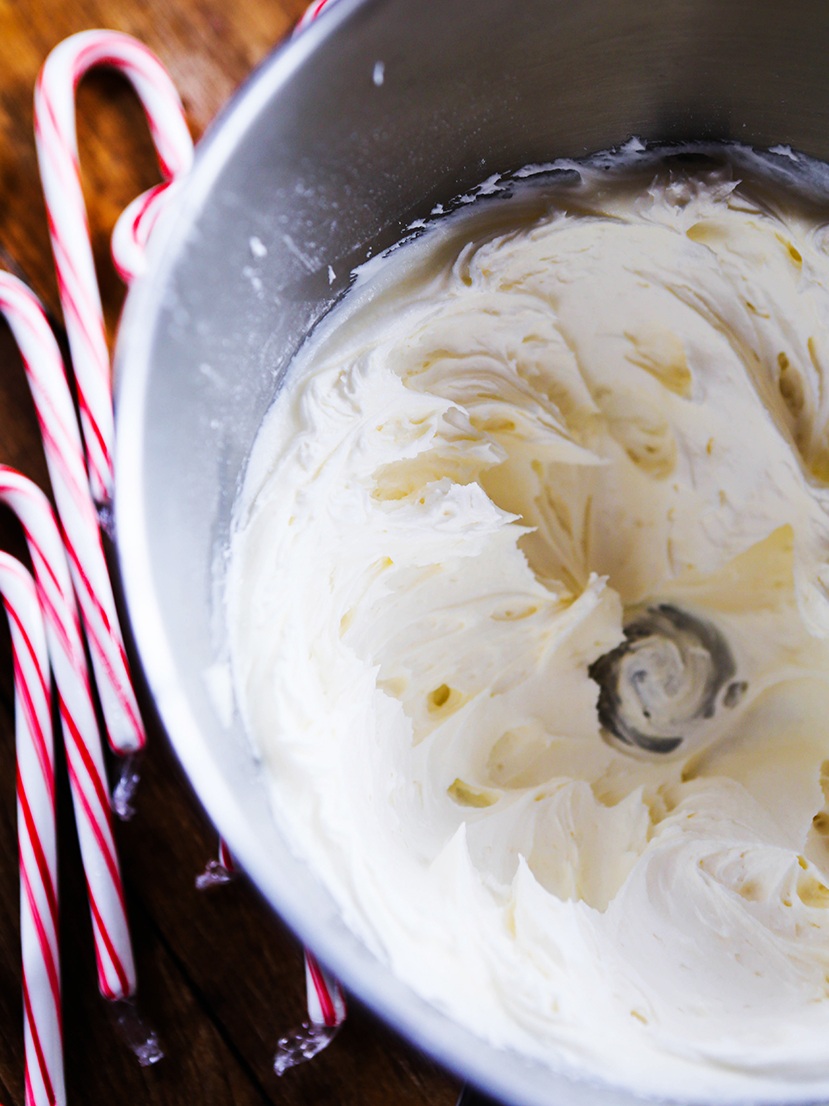 candy canes next to a bowl of peppermint buttercream