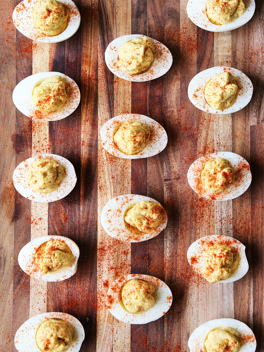 top view of deviled eggs lined up on a cutting board, sprinkled with paprika