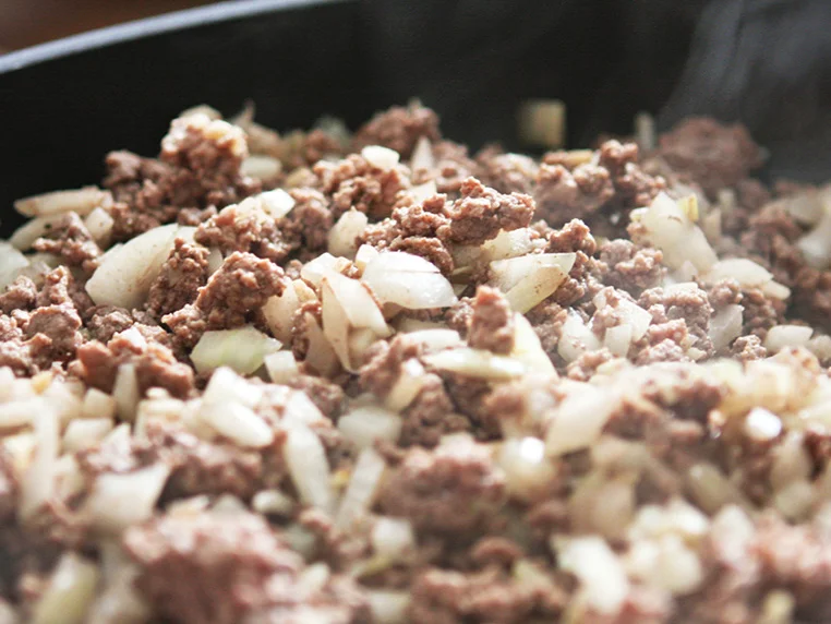  cooked ground beef and onions in a skillet 