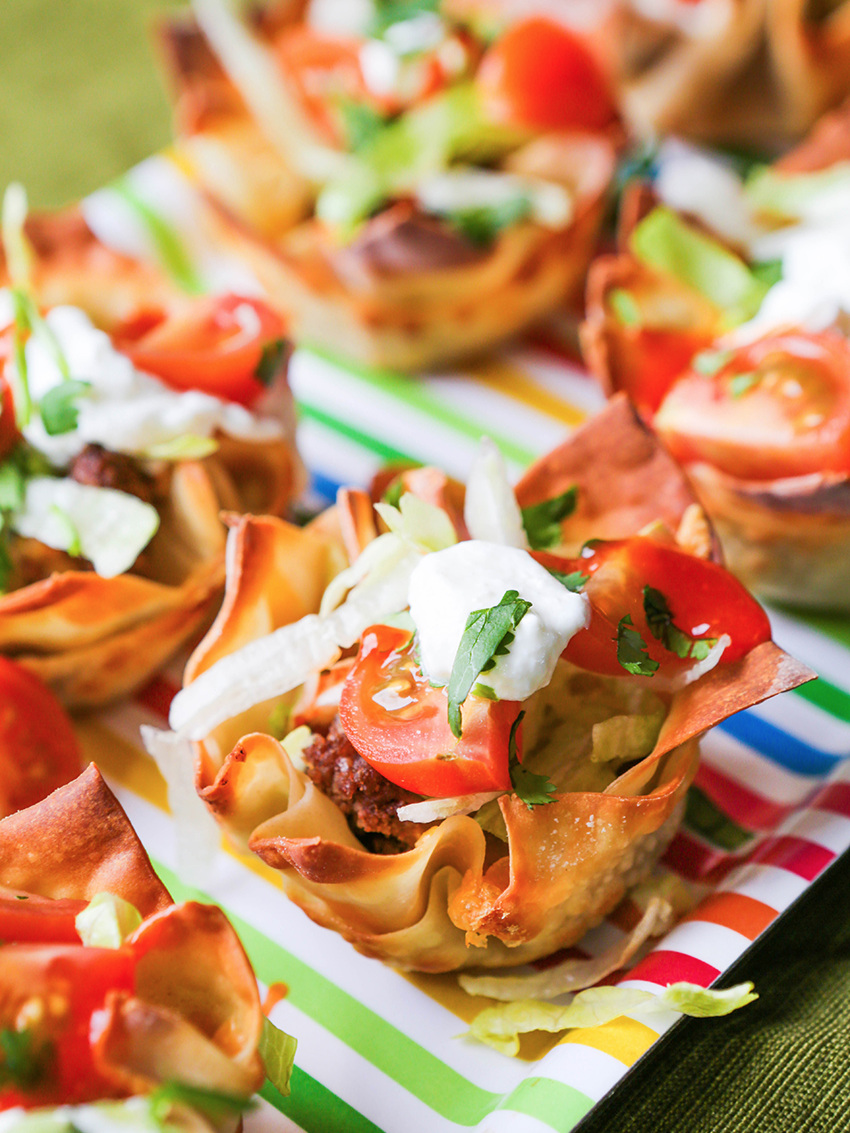 Close up view of a tray of loaded taco cups on the table cloth