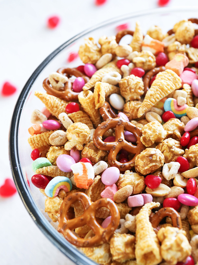 bowl filled with snack mix ingredients including pretzels, bugles and colored M&M's