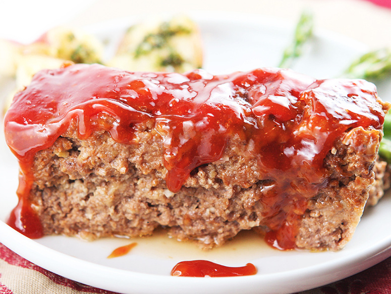 Slice of delicious meatloaf with sauce dripping over the sides - best dinner recipes of all time.