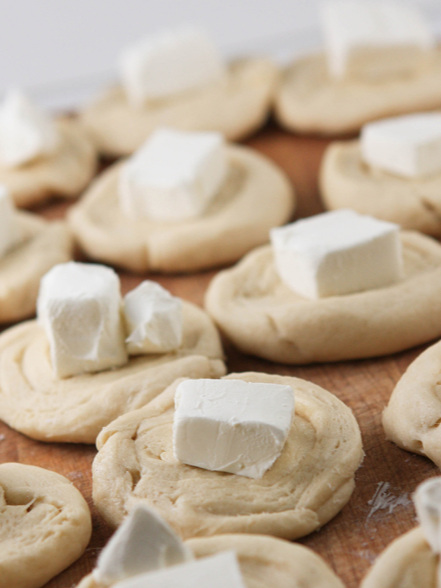 circles of dough with chunks of cream cheese on top each
