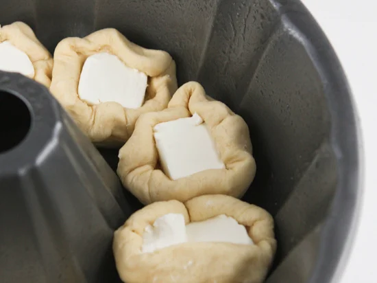 Bottom of a bundt pan lined with cream cheese filled pieces of dough