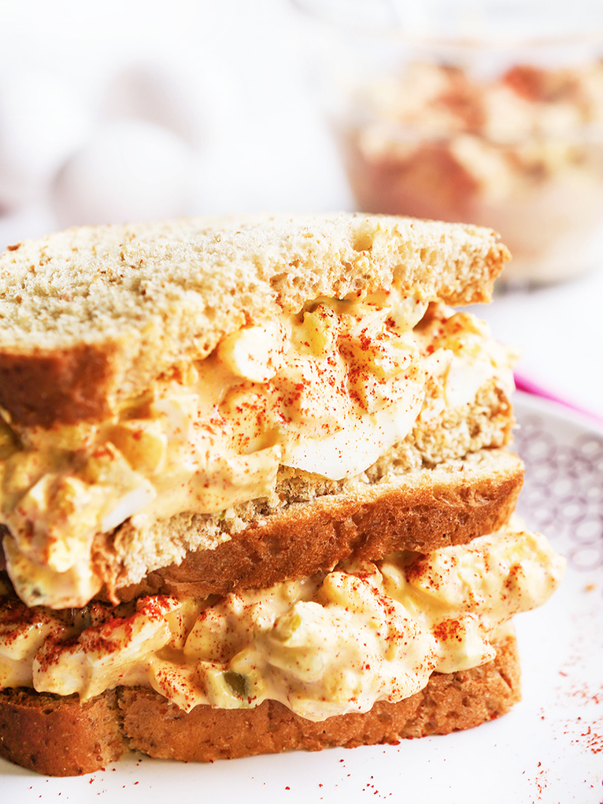 Stacked halves of egg salad sandwiches on a plate