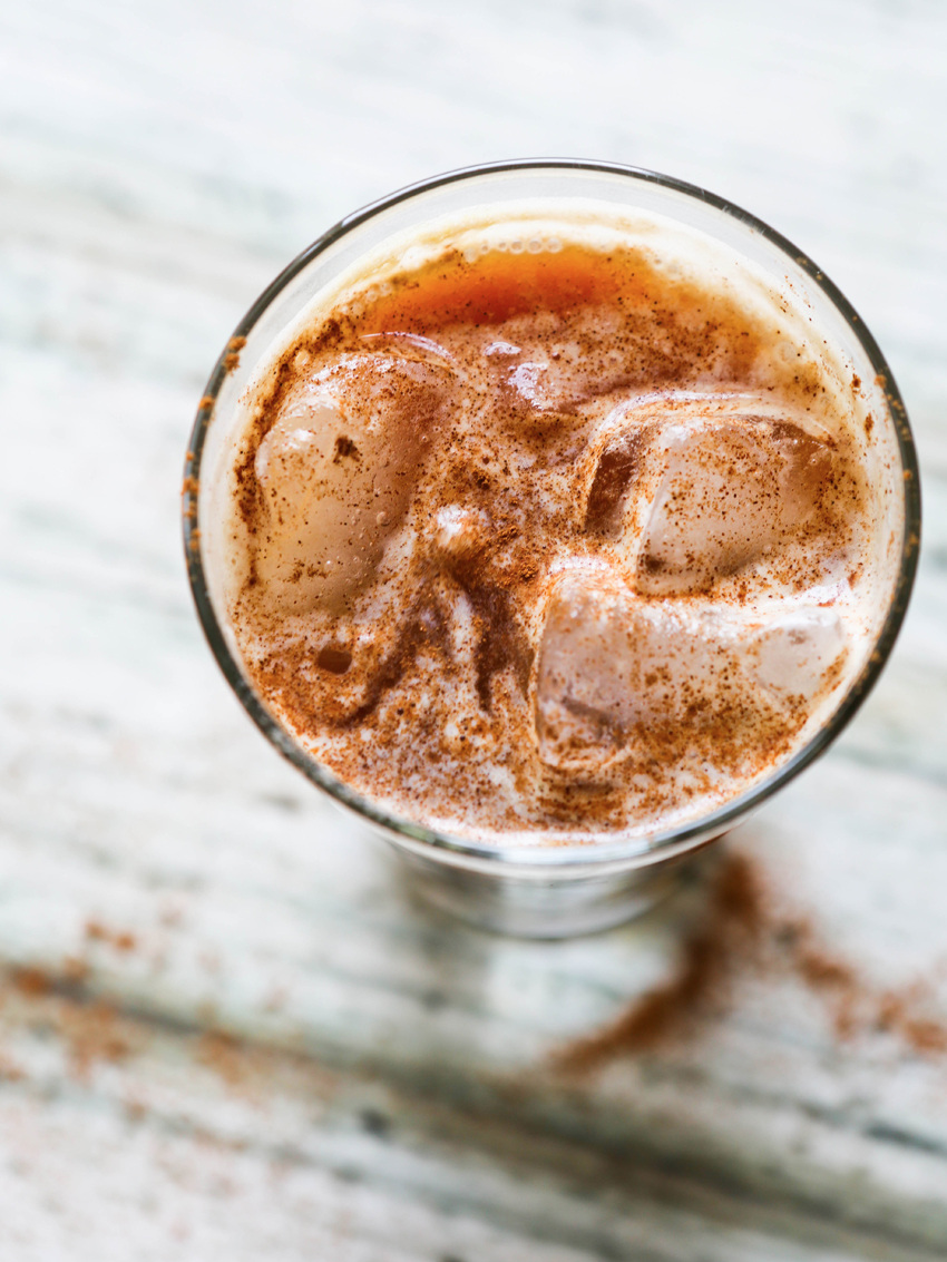 looking down into a swirly glass of a vanilla iced latte topped with cinnamon