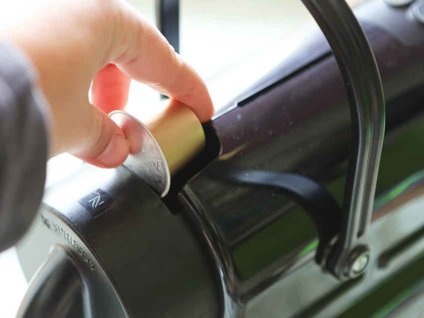 hand putting a capsule into a Nespresso machine