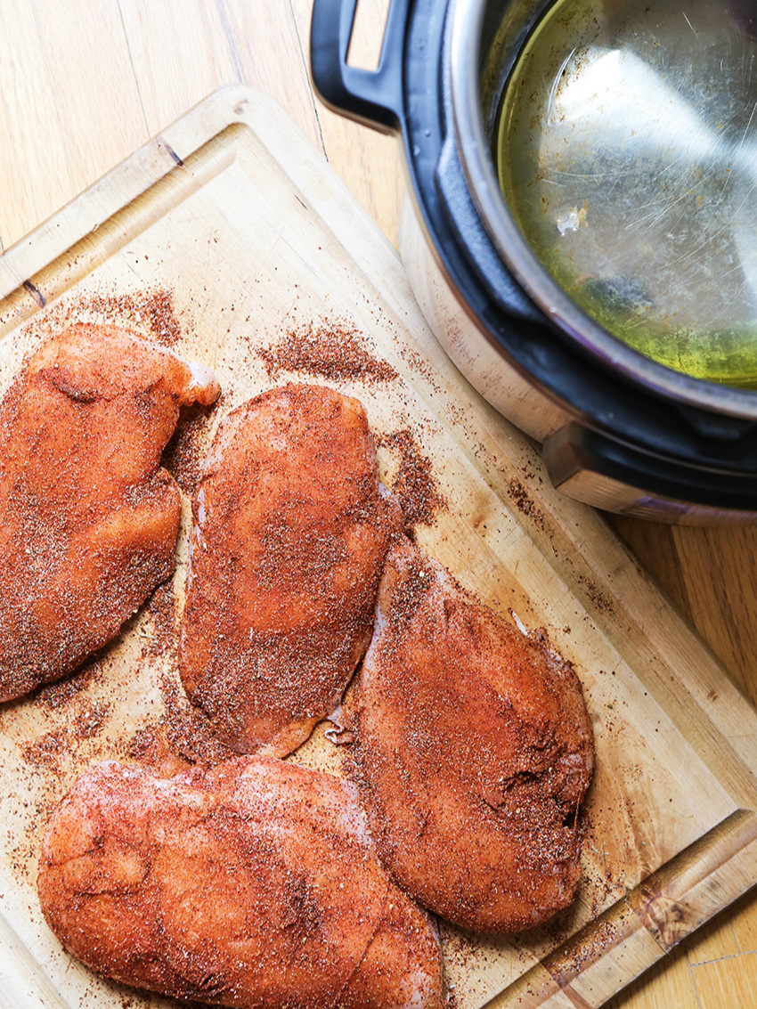 Chicken breasts covered in taco seasoning sitting by Instant Pot 