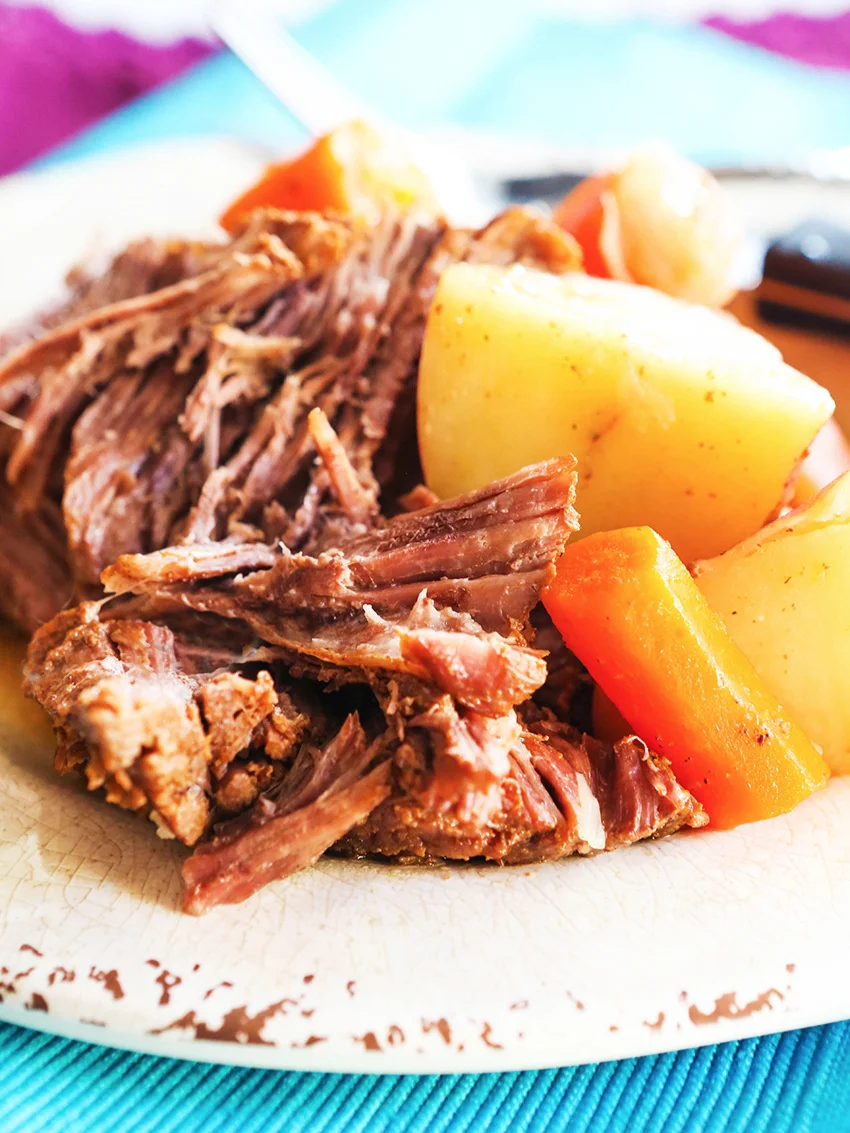 close up of a plate of pot roast, potatoes and carrots