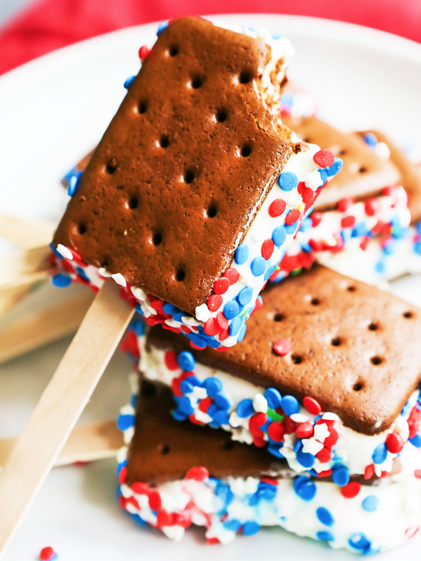 Stack of 4th of July dessert ice cream sandwiches with sprinkles on a plate with one missing a bite