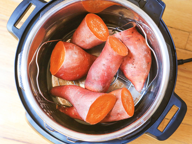looking down into an instant pot with halved cooked sweet potatoes
