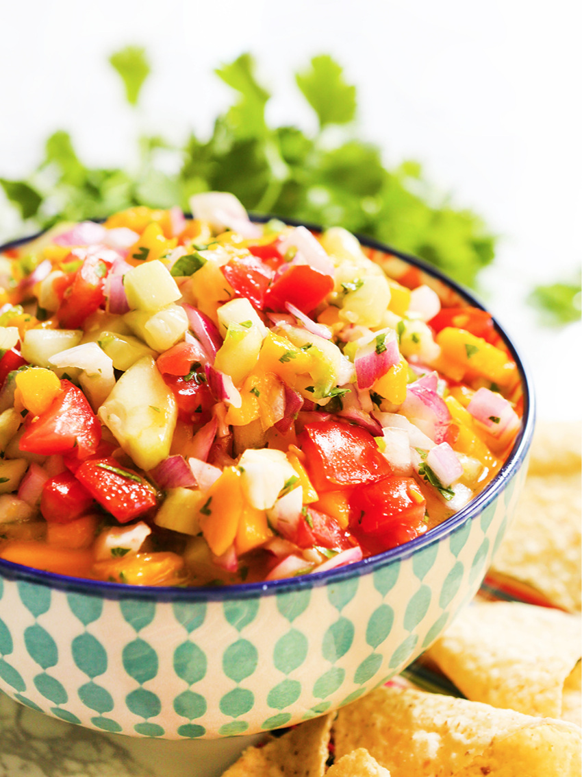close up of a heaping bowl of colorful salsa surrounded by chips