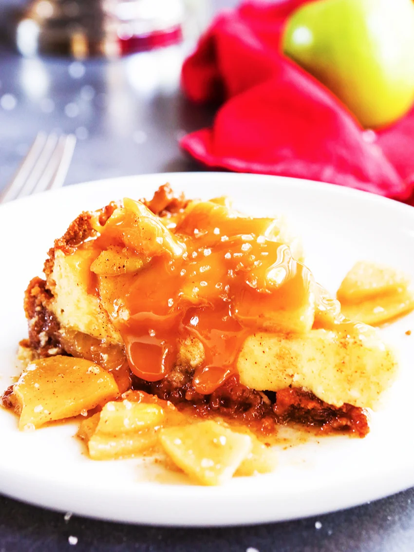 piece of salted caramel cheesecake on a serving plate with apples