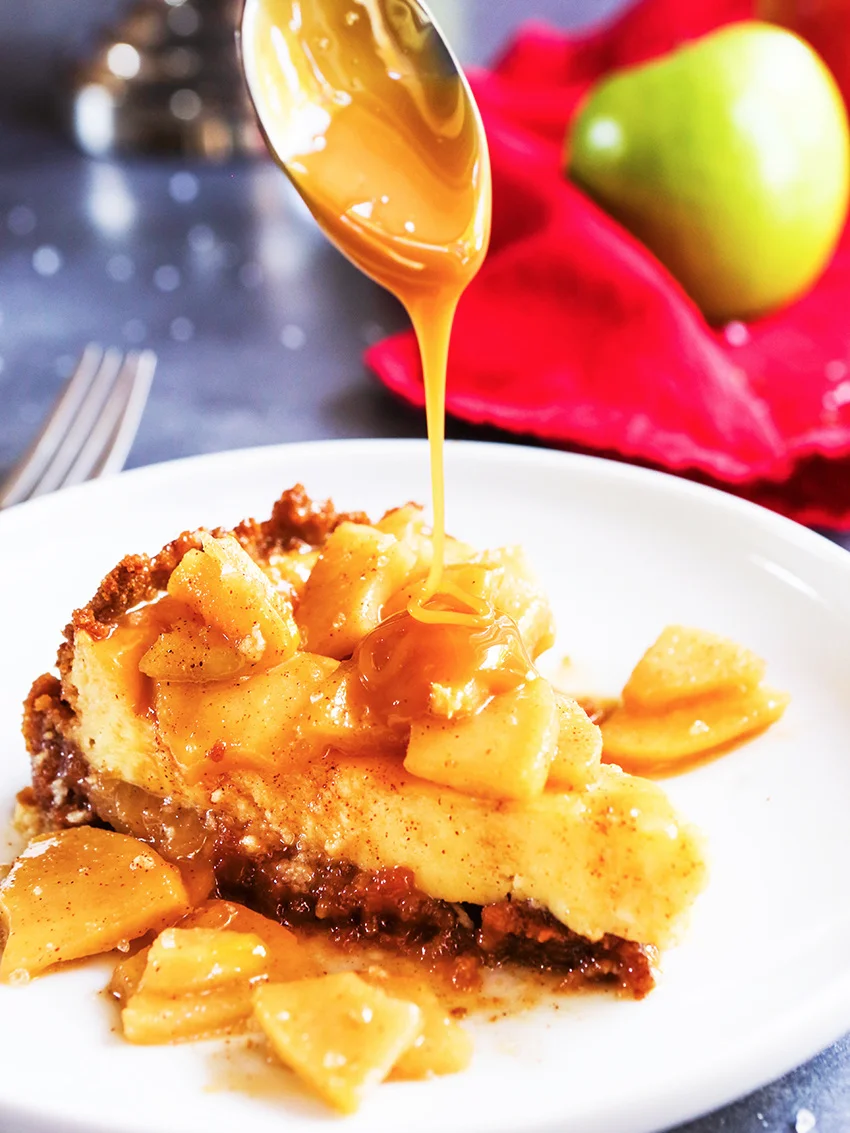spoon drizzling caramel sauce over apple cheesecake