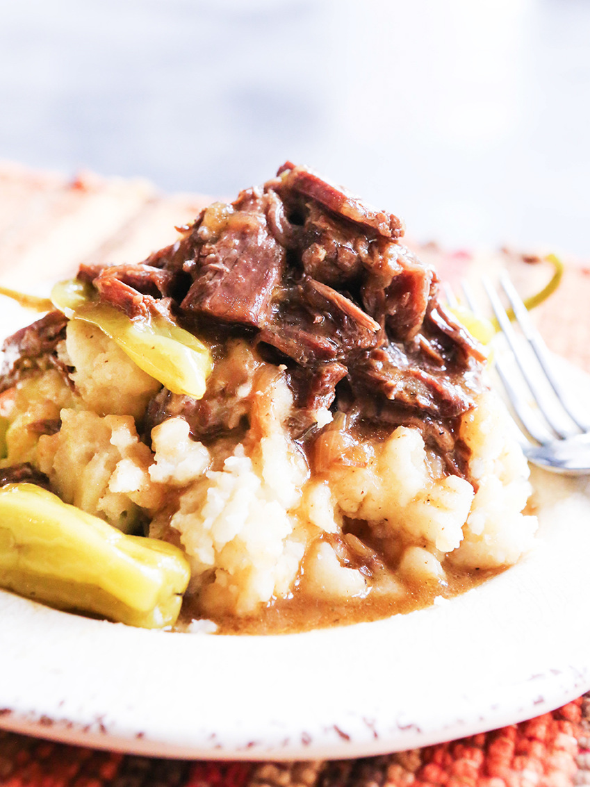 Shredded instant pot mississippi pot roast on top of mashed potatoes on a plate