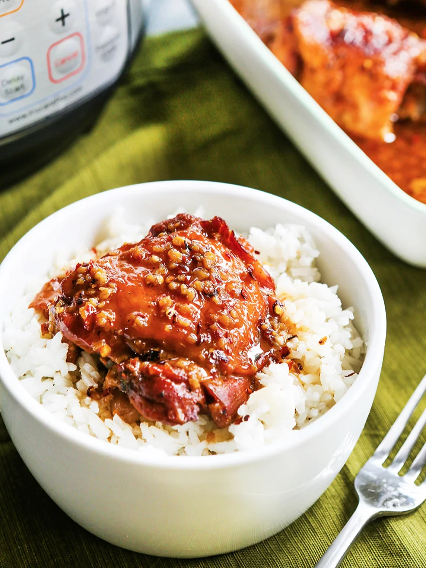 Bowl of instant pot honey garlic chicken and rice sitting next to the serving dish of chicken