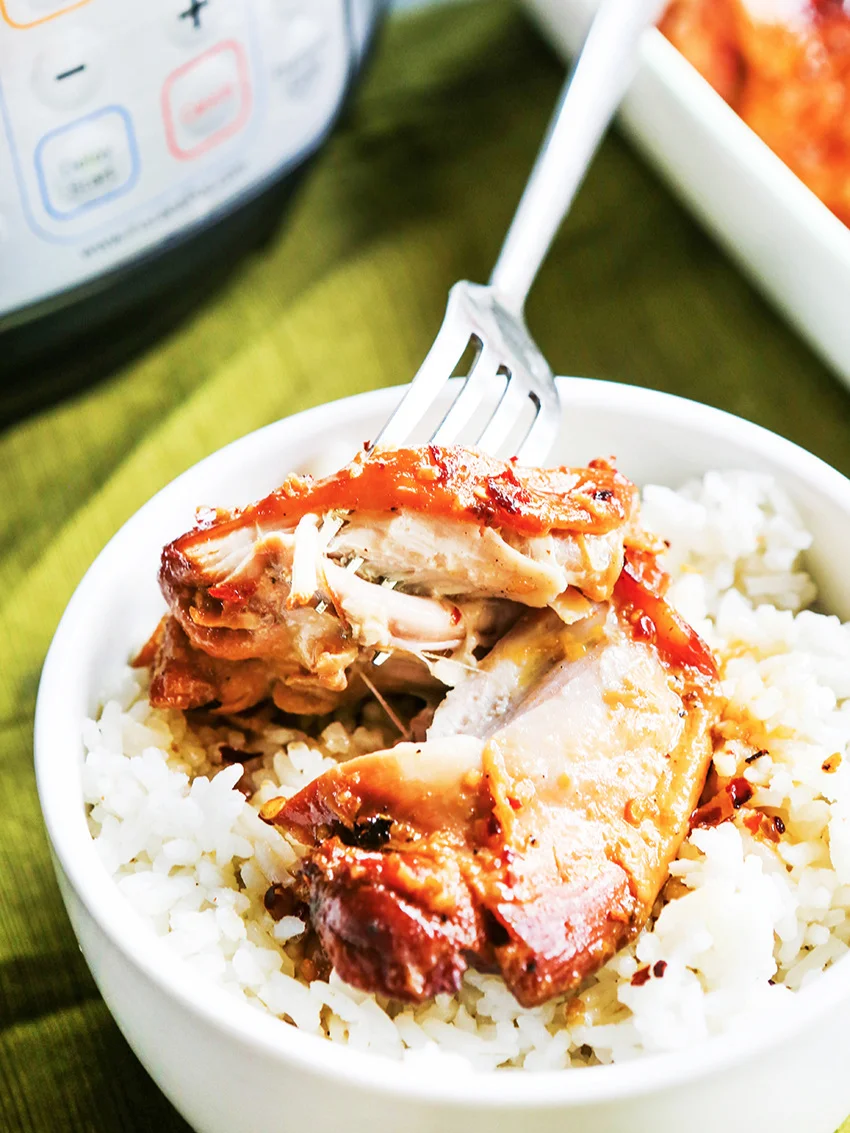 Bowl of rice with honey garlic chicken on top and a fork stuck in 