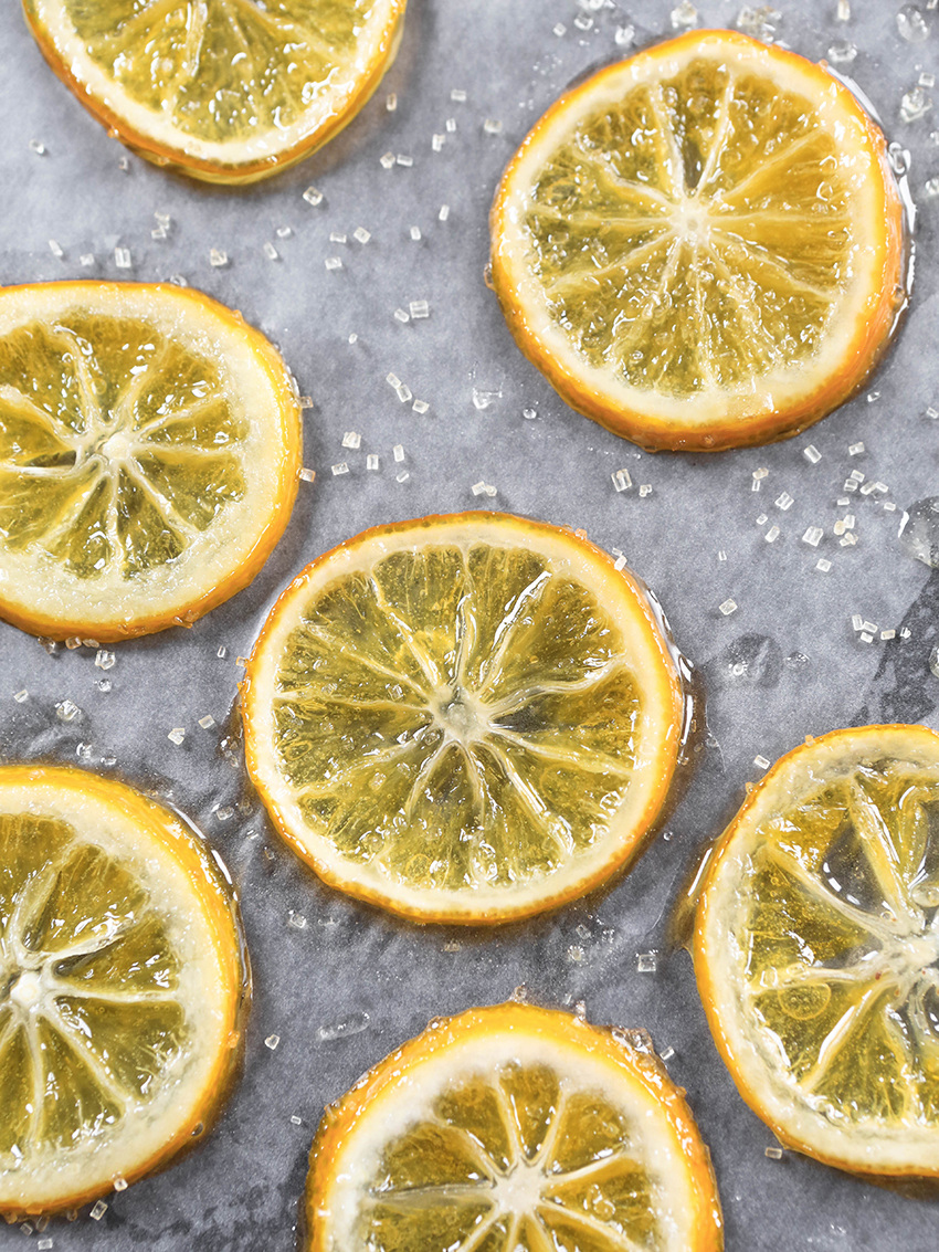 top view of candied lemon slices on parchment paper surrounded by sugar
