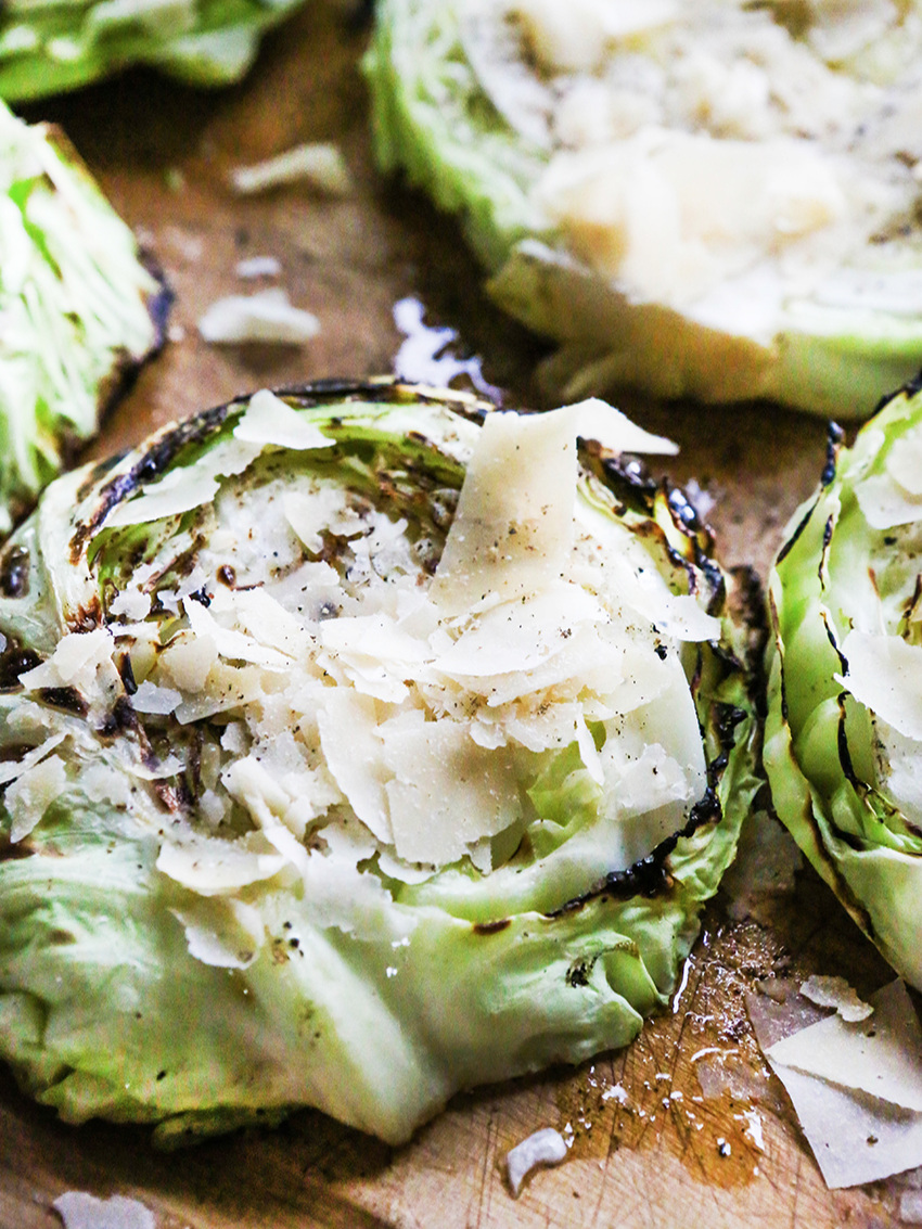 close up of grilled cabbage steaks with shaved parmesan on top